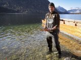 Beim Lechfischen, Fischereimeister Max Peinsteiner steht am Ufer des Grundlsees vor der Plätte mit Saiblingen in der Hand 
© ServusTV / WeBoom